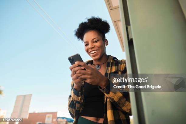 mid adult woman laughing during video chat in smart phone - femme et sourire photos et images de collection