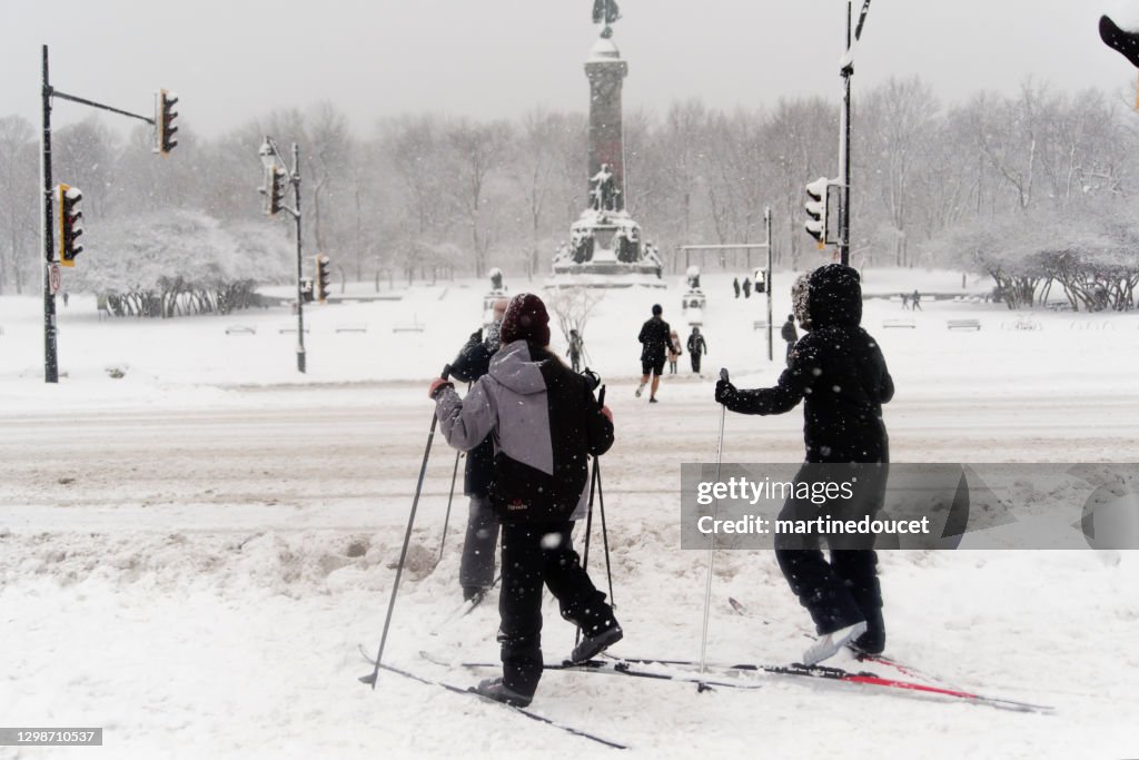 Madre e bambini attraversano la strada sul cielo di fondo nella tempesta di neve di Montreal.