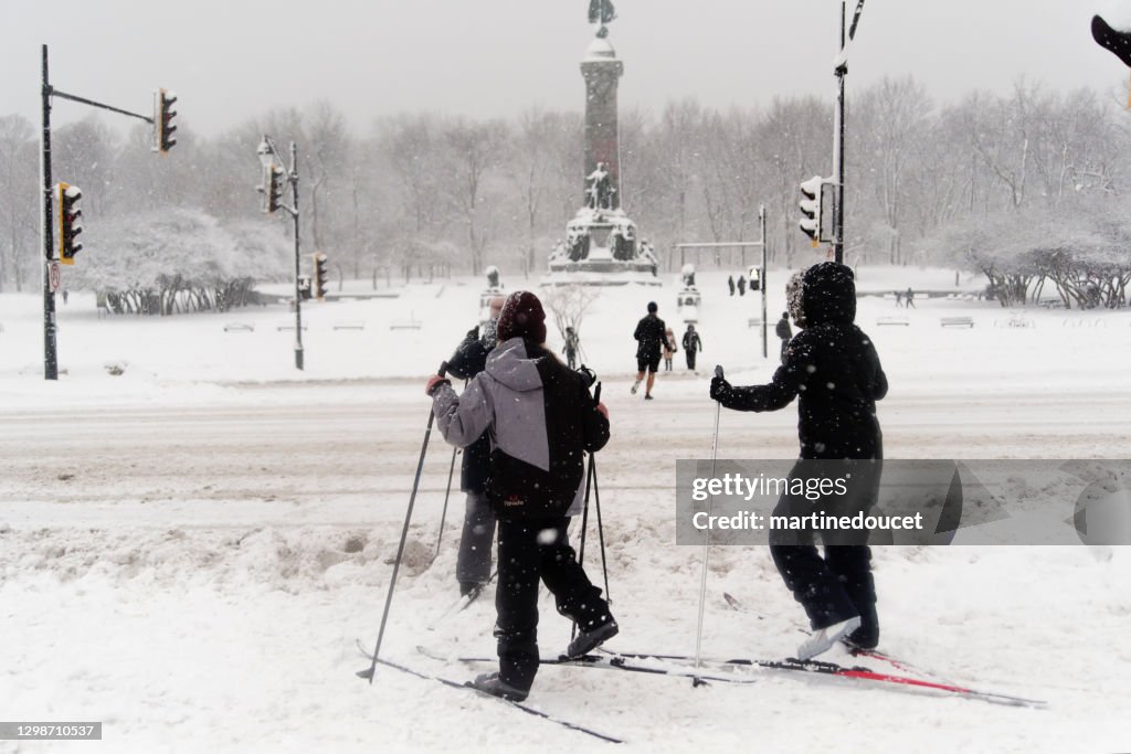Mother and children crossing street on cross-country sky in Montreal snow storm.