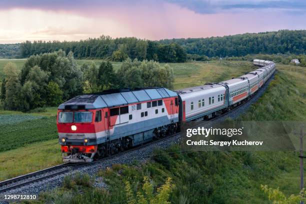 powerful diesel locomotive with passenger train moves in the beautiful countryside - lokomotive stock-fotos und bilder