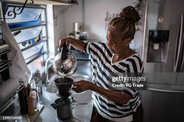 reife frau zubereiten kaffee zu hause - brewed coffee stock-fotos und bilder