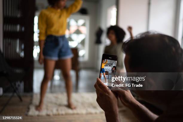 father filming on smartphone family dancing at home - youtuber stock pictures, royalty-free photos & images