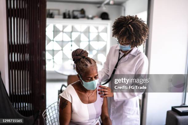 doctor using listening senior patient heartbeat during a home visit - using a face mask - brazil covid stock pictures, royalty-free photos & images