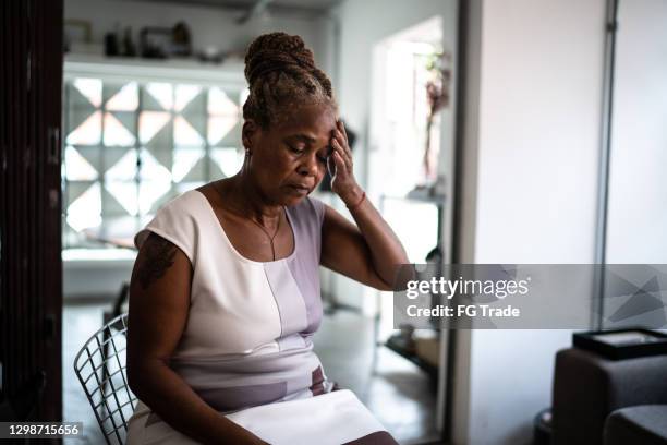 mature woman with headache at home - vulnerability stock pictures, royalty-free photos & images