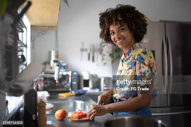 retrato de uma jovem cortando comida em casa - homemaker - fotografias e filmes do acervo