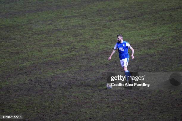 Mark Beevers of Peterborough United runs with the ball on a muddy pitch during the Sky Bet League One match between Peterborough United and Bristol...