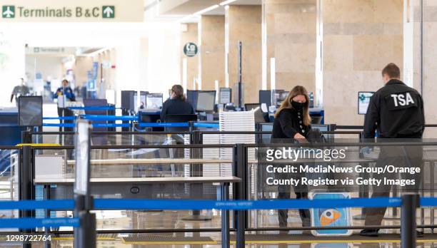 Agent helps a traveler through security at a nearly deserted checkpoint at John Wayne Airport in Santa Ana, CA on Tuesday, January 26, 2021....