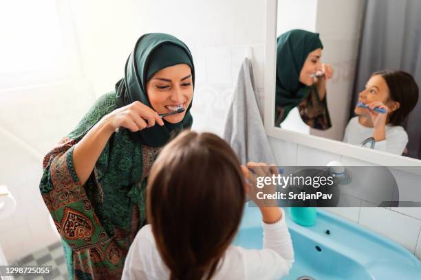 happy muslim mother and daughter brushing their teeth together - brushing teeth stock pictures, royalty-free photos & images