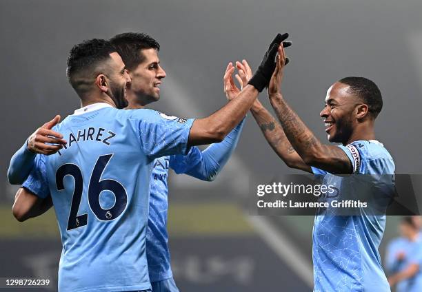 Raheem Sterling of Manchester City celebrates with Riyad Mahrez and Rodri after scoring their team's fifth goal during the Premier League match...