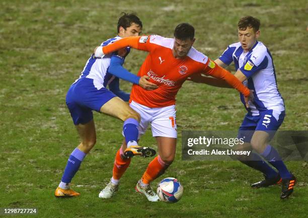 Gary Madine of Blackpool is tackled by George Johnston and Alex Perry of Wigan Athletic during the Sky Bet League One match between Wigan Athletic...