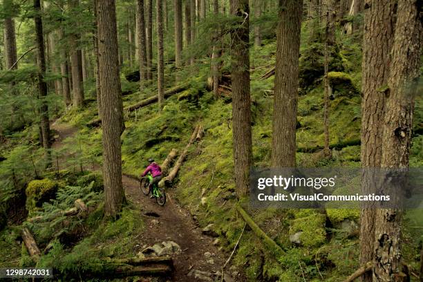 frau mountainbiken durch pacific west coast regenwald. - trail britisch kolumbien stock-fotos und bilder