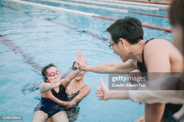 asian chinese parent high five cheering encouraging their children learning swimming class at poolside - coach cheering stock pictures, royalty-free photos & images