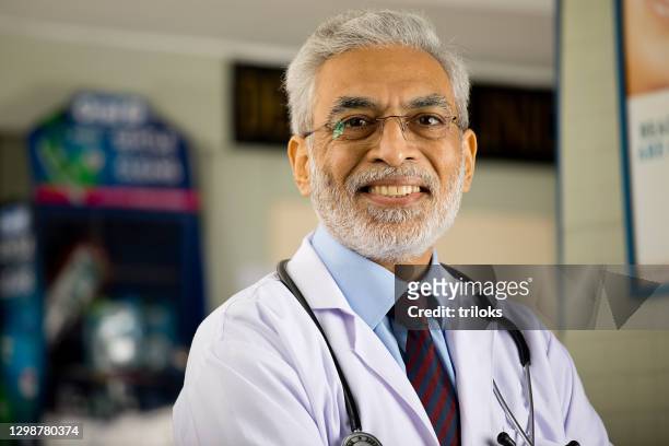 medico maschio anziano che guarda la macchina fotografica - india doctor foto e immagini stock