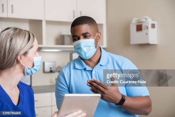 adult man telling nurse his symptoms in exam room - mask man stock pictures, royalty-free photos & images