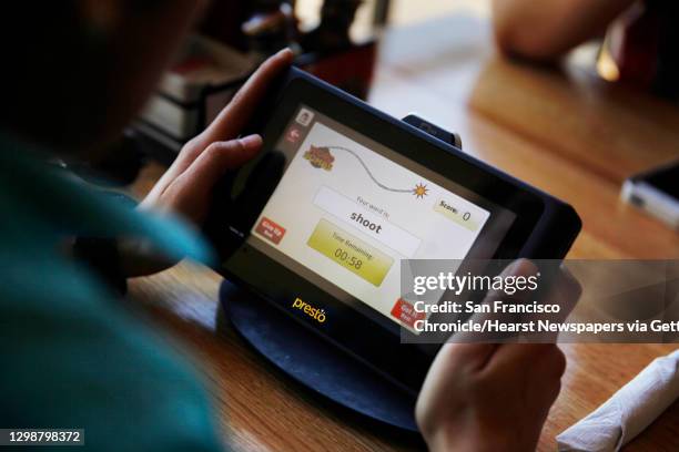 Gloria Garcia, of Livingston, holds a tablet while playing a game on a tablet at Applebee's in Fisherman's Wharf on Thursday, April 10 in San...