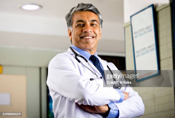 portrait of confident male doctor looking at camera - males stock pictures, royalty-free photos & images