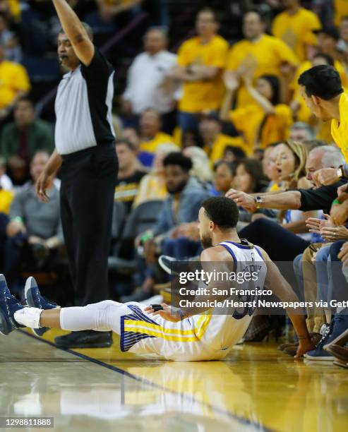 Golden State Warriors� Stephen Curry slides into fans after shooting over Portland Trail Blazers� CJ McCollum in the second quarter during game 1 of...