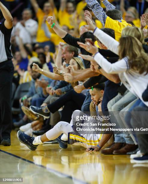 Golden State Warriors� Stephen Curry slides into fans after shooting over Portland Trail Blazers� CJ McCollum in the second quarter during game 1 of...