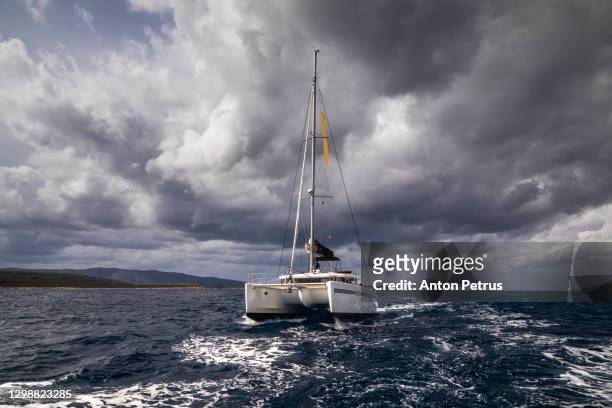 catamaran in a stormy sea in dramatic weather - thunderstorm ocean blue stock pictures, royalty-free photos & images