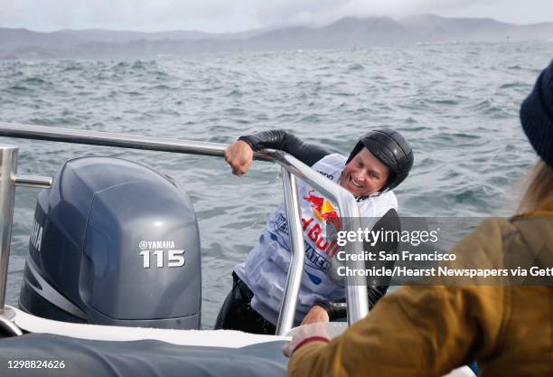 John Hadley, a paddleboard racer from Forestville in Sonoma County, climbs aboard a support boat to hitch a ride to the starting line of the Red Bull...