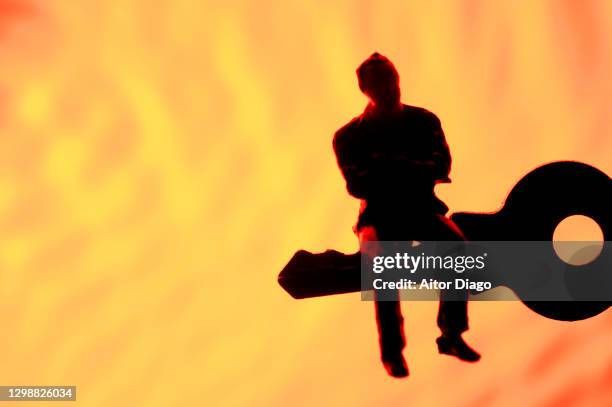 person sitting on a key with interlaced orange lines forming a net  background with a net in the background. - ransomware stock pictures, royalty-free photos & images