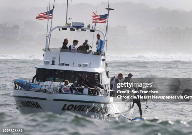 Participants hop off of the Lovely Martha into turbulent waves before the start of the Red Bull Heavy Water stand-up paddleboard race in San...