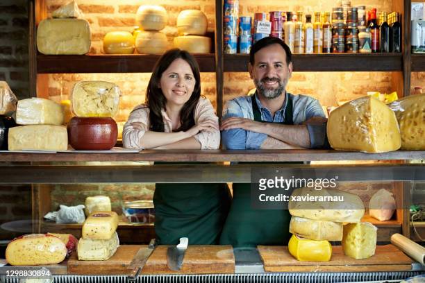 食品店の小売ディスプレイの背後にあるチーズモンガーの肖像画 - アルチザンフード ストックフォトと画像