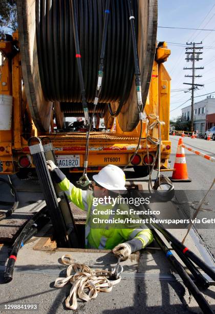 Lloyd Ratzlaff, with Pinnacle Power get set to install P.G. & E. Power lines underground through the utility vault he is climbing into along Old...