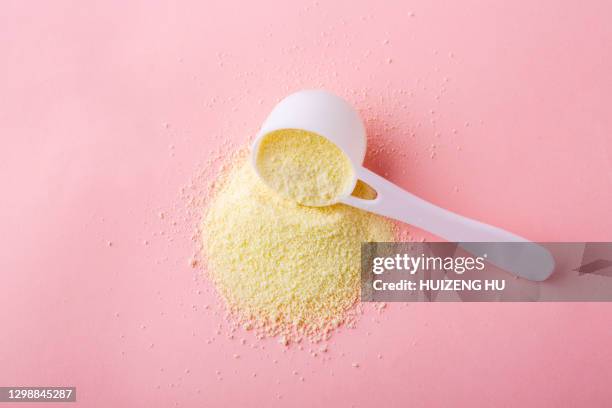 powdered milk in plastic spoon on pink background - milchpulver stock-fotos und bilder