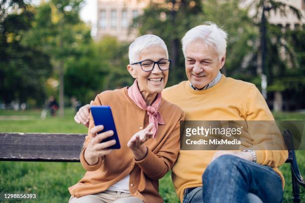 coppia senior che si rilassa nel parco e naviga in rete - 55 59 anni foto e immagini stock