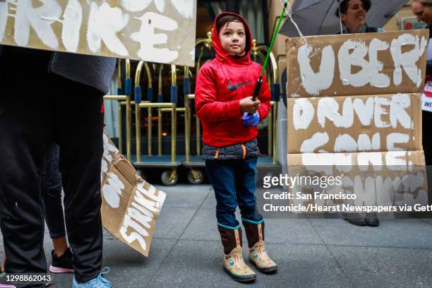 Cameron McConnell, 7 holds up a homeade sign that says ""Uber Driver Gone Fishing"" as he stands alongside his father Gregory McConnell during a...
