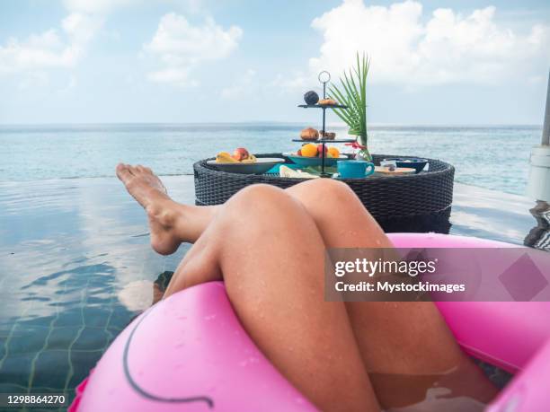 pov der frau in aufblasbaren flamingo schwimmen auf infinity-pool in der nähe von frühstück tablett - women with nice legs stock-fotos und bilder