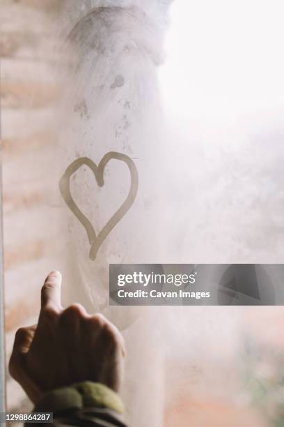 man drawing with his finger a heart in wet window - man in fog drawing stock pictures, royalty-free photos & images
