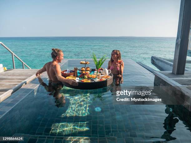 paar genießen schwimmendes frühstück in privaten overwater bungalow - maldivas stock-fotos und bilder