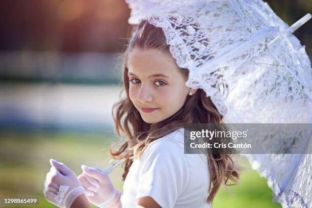 young girl wearing first communion dress outdoors with umbrella - forma-di-comunicazione foto e immagini stock