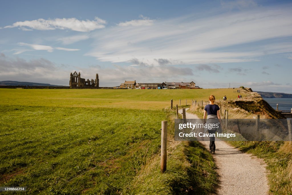 Woman walking along path between Whitby and Robinshood Bay with