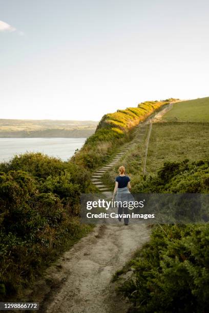 red headed woman walking along path between whitby and robinshoo - whitby north yorkshire england stock pictures, royalty-free photos & images