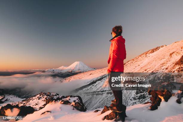 young woman on red jacket watching mt ngauruhoe, tongariro national park, new zealand - new zealand ski stock pictures, royalty-free photos & images