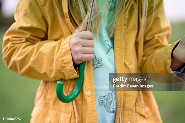 middle view of girl holding umbrella in yellow rain coat - regnkläder bildbanksfoton och bilder