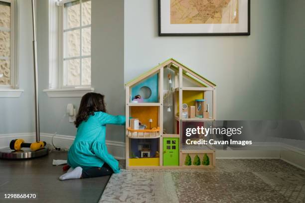 young girl playing with dollhouse in living room - casa de boneca - fotografias e filmes do acervo