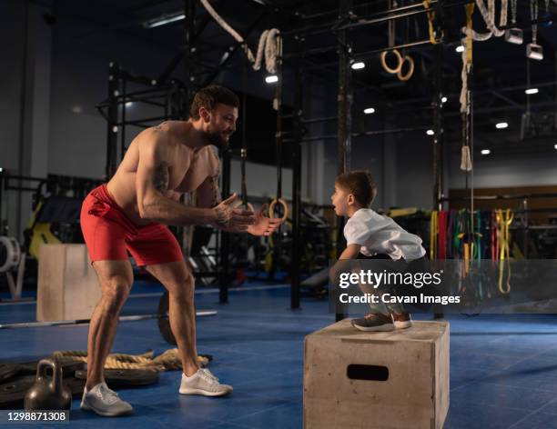 son jumping to father in gym - boxing trainer stock pictures, royalty-free photos & images