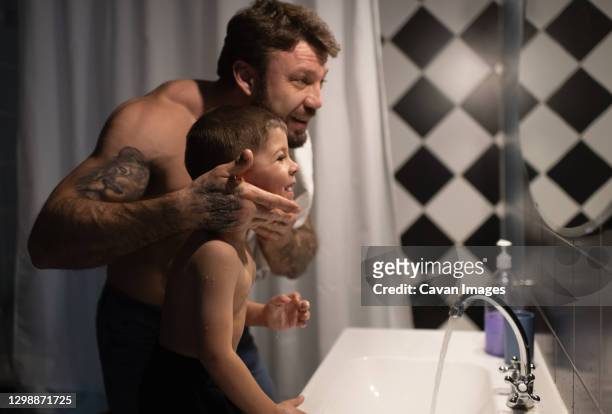 father and son looking at mirror after shaving - domestic bathroom - fotografias e filmes do acervo