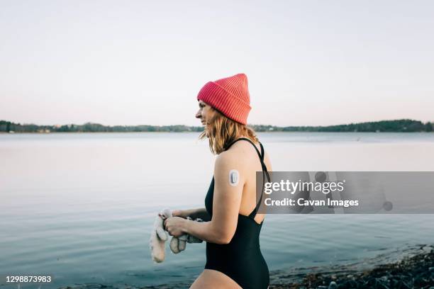 woman entering the calm water ready for cold water swimming in sweden - taking the plunge 個照片及圖片檔
