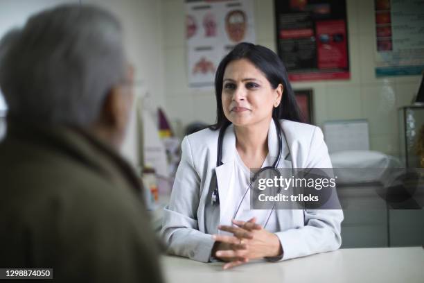 female doctor consulting and giving advice to old male patient - pharmacist and patient imagens e fotografias de stock