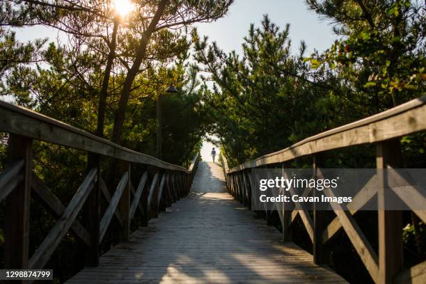 a small child is silhouetted in the distance at end of long boardwalk - bethany beach - fotografias e filmes do acervo