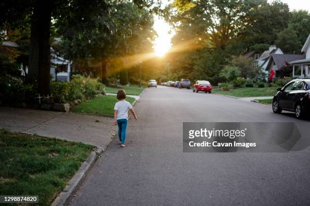 a small girl walks barefoot down a suburban street alone at sunset - columbus ohio neighborhood stock pictures, royalty-free photos & images