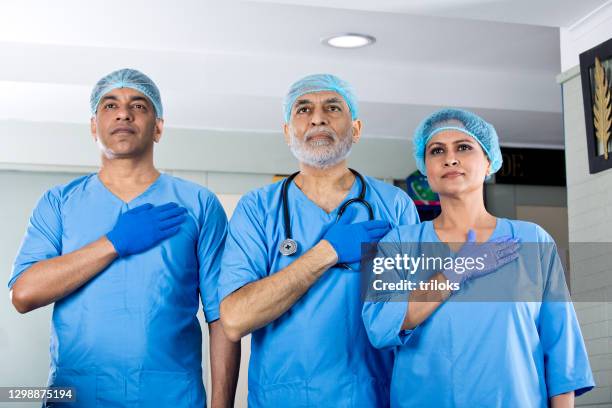 gelukkige chirurgen met handen op borst - oath stockfoto's en -beelden