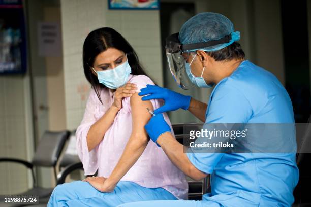 doctor injecting vaccine to female patient - moving activity stock pictures, royalty-free photos & images