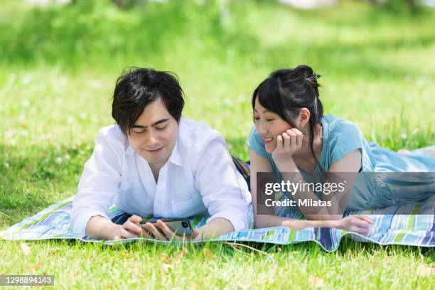 a couple looking at a smartphone - woman smiling facing down stock pictures, royalty-free photos & images