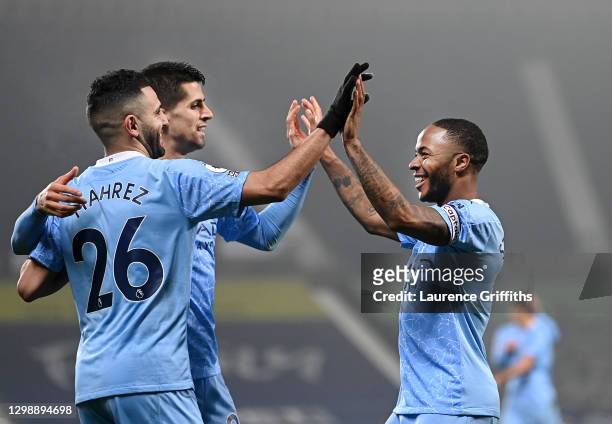 Raheem Sterling of Manchester City celebrates after scoring his sides fifth goal with team-mates Riyad Mahrez and Joao Cancelo during the Premier...